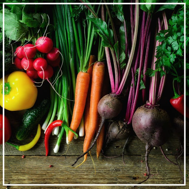 Collection of mixed vegies freshly harvested from the garden laying on a wooden benchtop