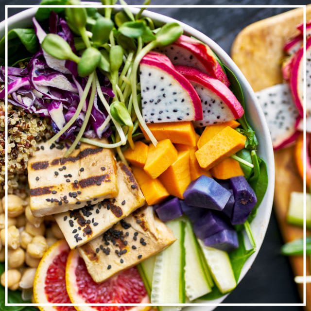 Large white bowl of sliced fresh fruits with grilled tofu