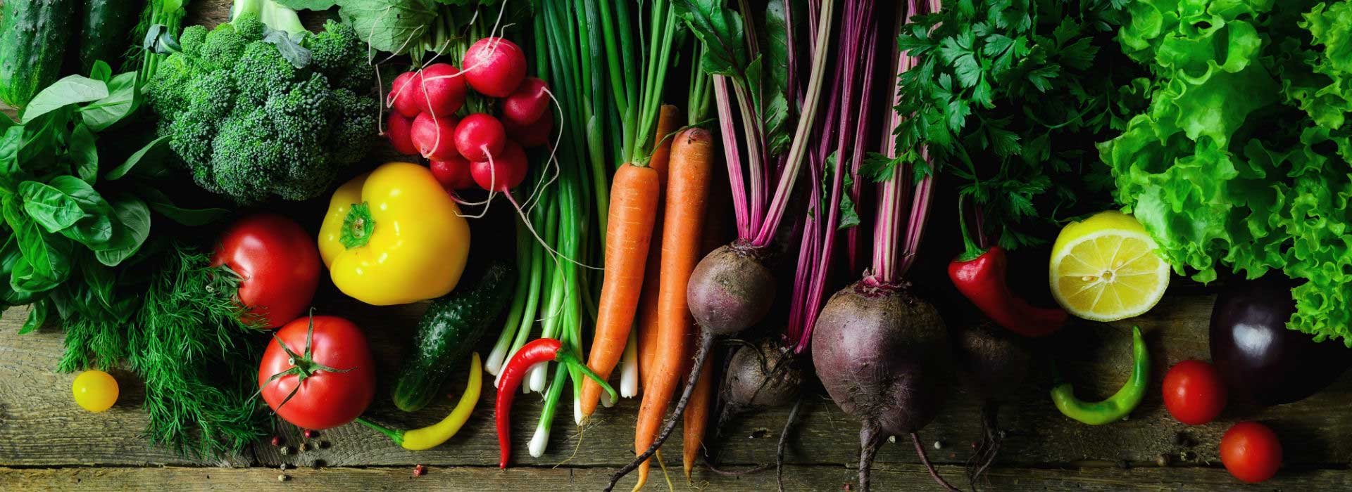 raw fruits and vegetables laid out on a wooden bench